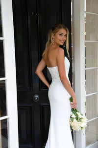 Back Image of White Minimalist Satin Bridal Gown with Strapless Scoop Neckline and Gathered Detail worn with dangling pearl earrings