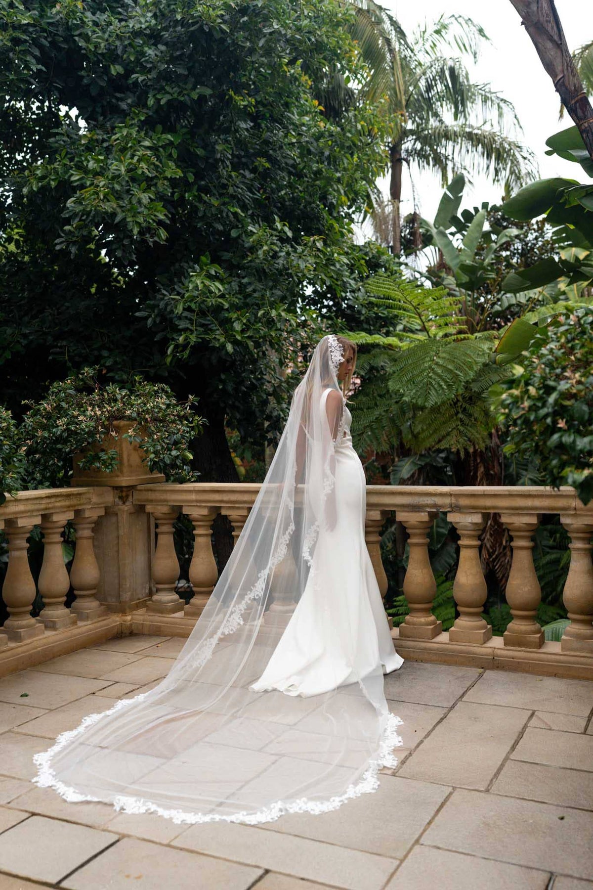 A bride wearing a cathedral long sheer veil with floral lace edging detail viewed from behind
