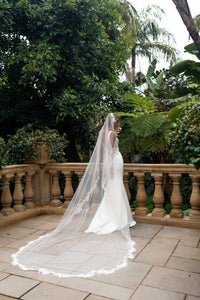 A bride wearing a cathedral long sheer veil with floral lace edging detail viewed from behind