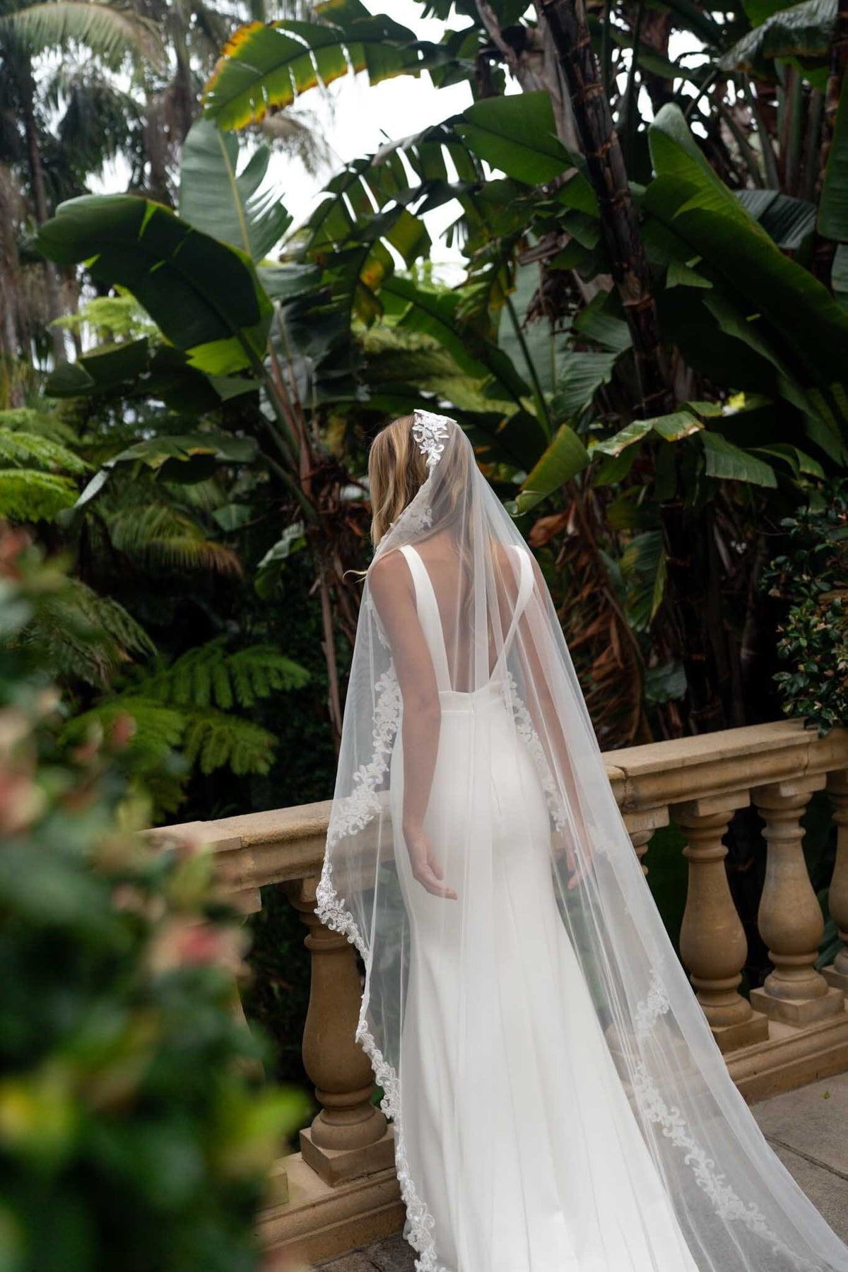 A bride wearing a long sheer veil with lace edging detail