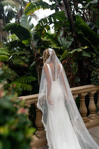 A bride wearing a long sheer veil with lace edging detail