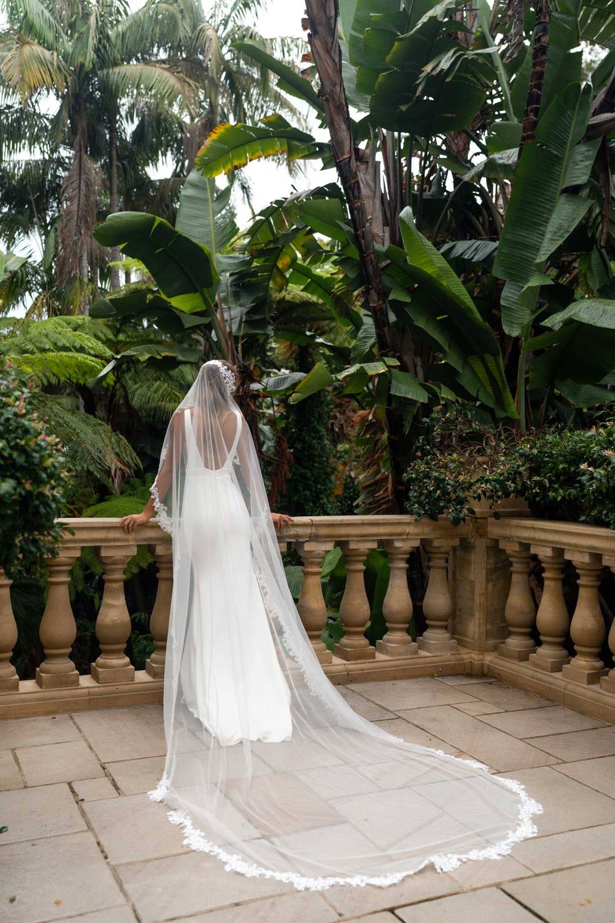 A bride wearing a cathedral long sheer veil with floral lace edging detail viewed from behind