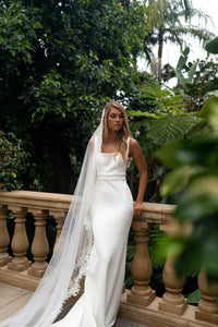 A bride wearing a long sheer veil with lace edging detail