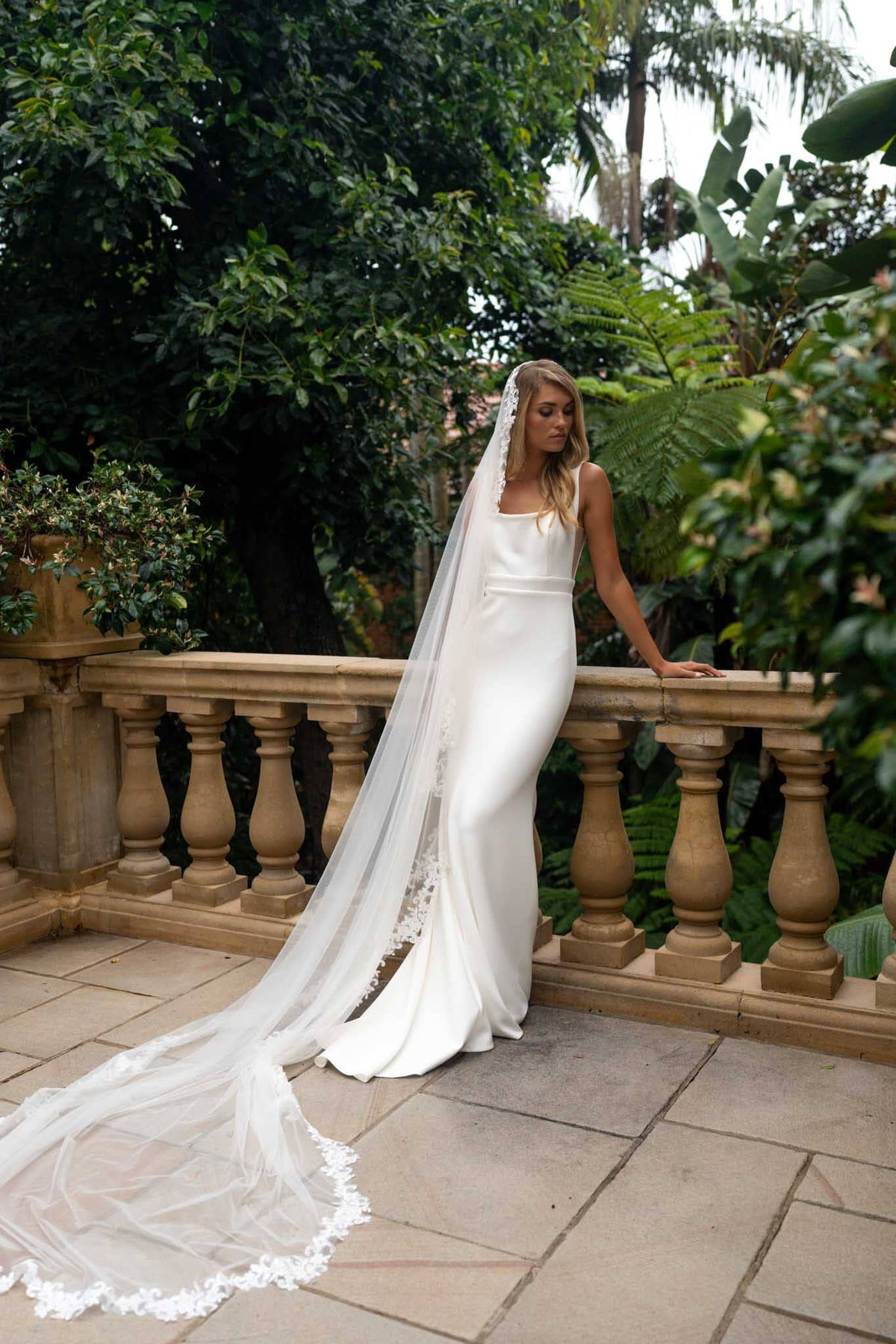 A bride wearing a long sheer veil with lace edging detail
