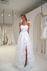 Young bride wearing a white floral wedding dress in a fitting room setting