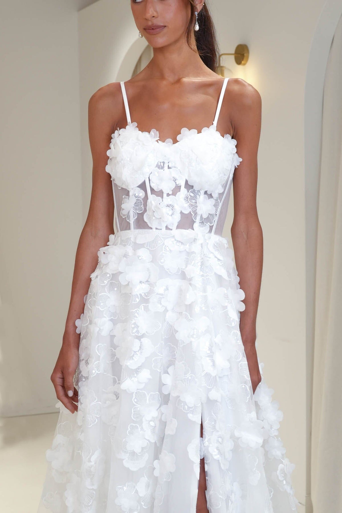 Close up image of Francine 3D floral wedding dress featuring sheer corset bodice, hand-sewn flower appliques and thigh high side slit