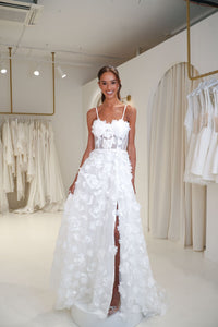 Francine 3D floral wedding gown featuring sheer corset bodice, hand-sewn flower appliques, A-line skirt and thigh high side slit