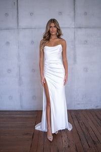 White bustier strapless fitted stretch satin wedding gown with draped pleats and high side slit
