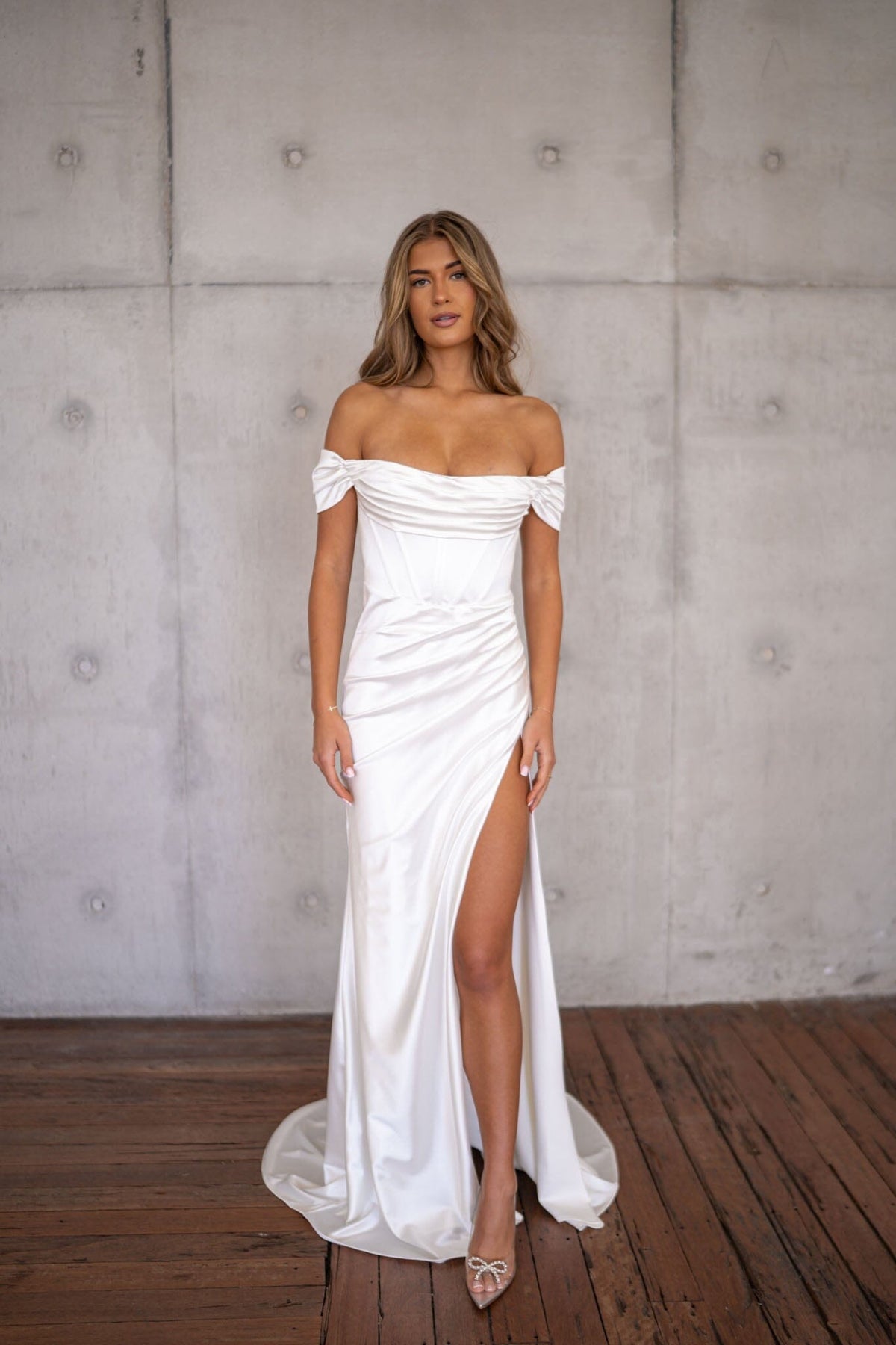 White off-the-shoulder fitted wedding dress with draped detail and a high slit
