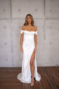 White off-the-shoulder fitted wedding dress with draped detail and a high slit