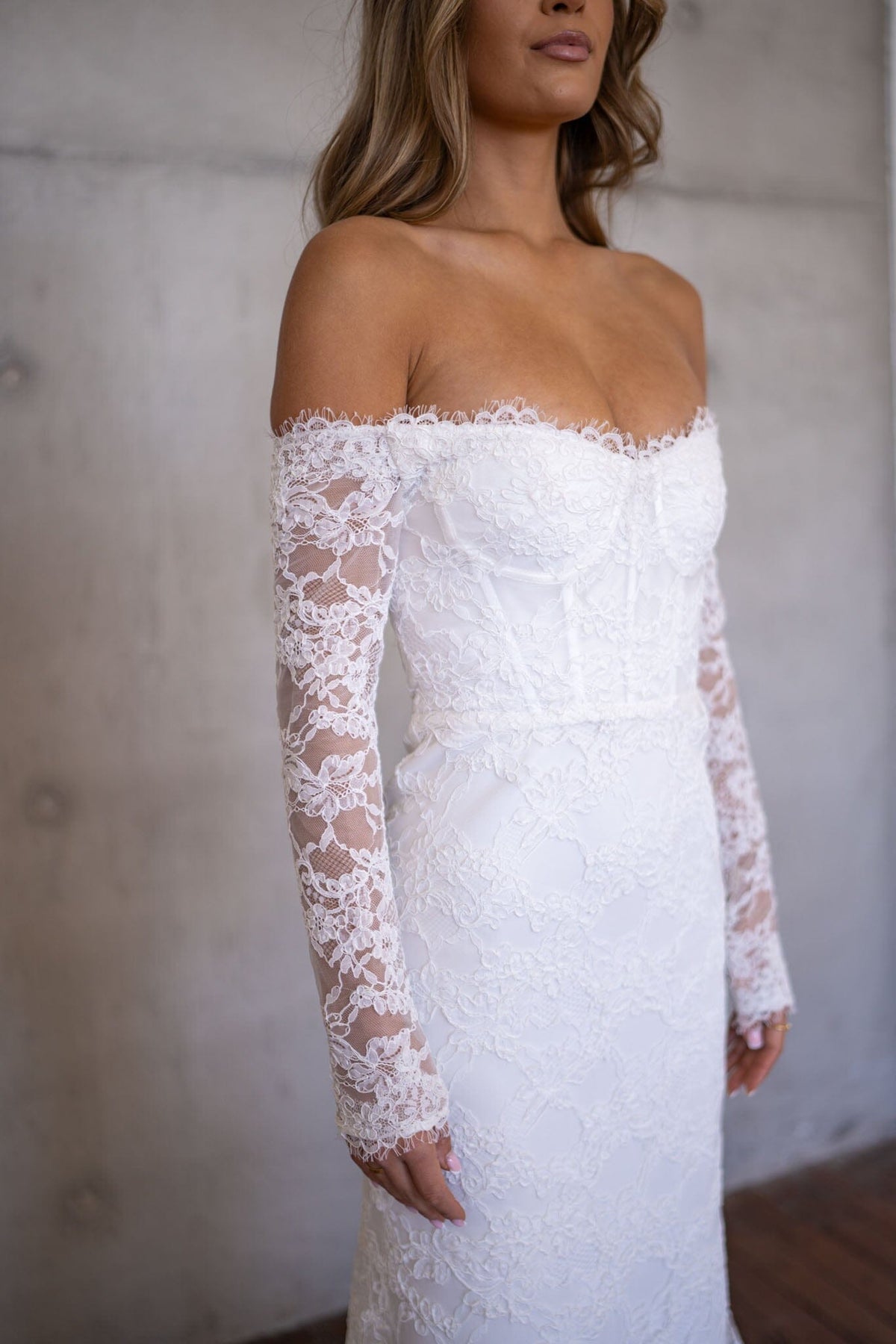 Close Up Image of Lace Detail on Sheer Long Sleeve of Ivory White Off The Shoulder Long Sleeve Lace Wedding Gown with Sweetheart Neckline and Corset Bodice