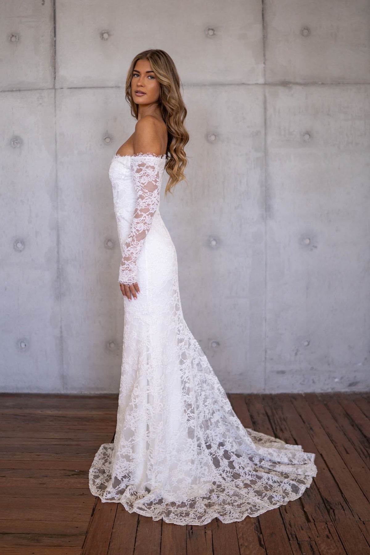 Side Image of Ivory White Off The Shoulder Long Sleeve Lace Wedding Gown with Sweetheart Neckline, Corset Bodice and Fit and Flare Mermaid Silhouette