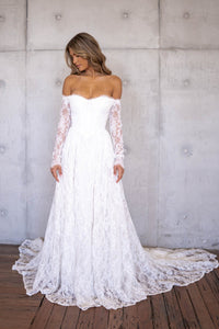 Ivory White Off The Shoulder Long Sleeve Lace Wedding Gown featuring Sweetheart Neckline with Lace Trimming Detail, Sheer Long Sleeves, Corset Bodice, Basque Waistline, Full A-line Skirt and Long Train.