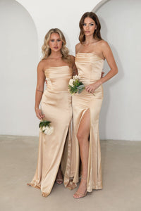 Two Bridesmaids wearing Neutral Gold Champagne Coloured Strapless Satin Maxi Dress with Draped Detail at Bust and Side Slit