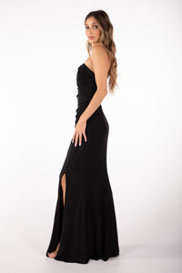 Side image of Shimmer Black maxi dress featuring asymmetrical one shoulder neckline, a bodycon fit with gathering detail at the front and thigh-high leg slit
