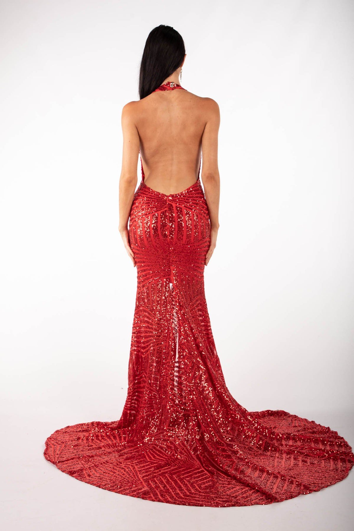 Backless design of red geometric sequin evening gown featuring halter V plunge neckline, high center front split, open back and sweep train